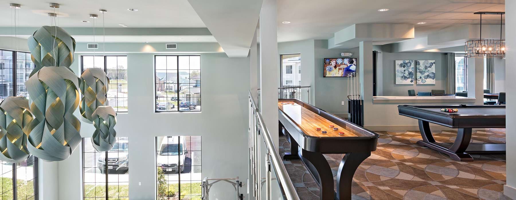 second floor game lounge with shuffleboard and billiards overlooking first floor fitness center